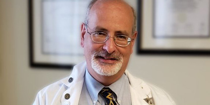 Ronald Schwartz MD wearing a doctor's coat smiling at camera.